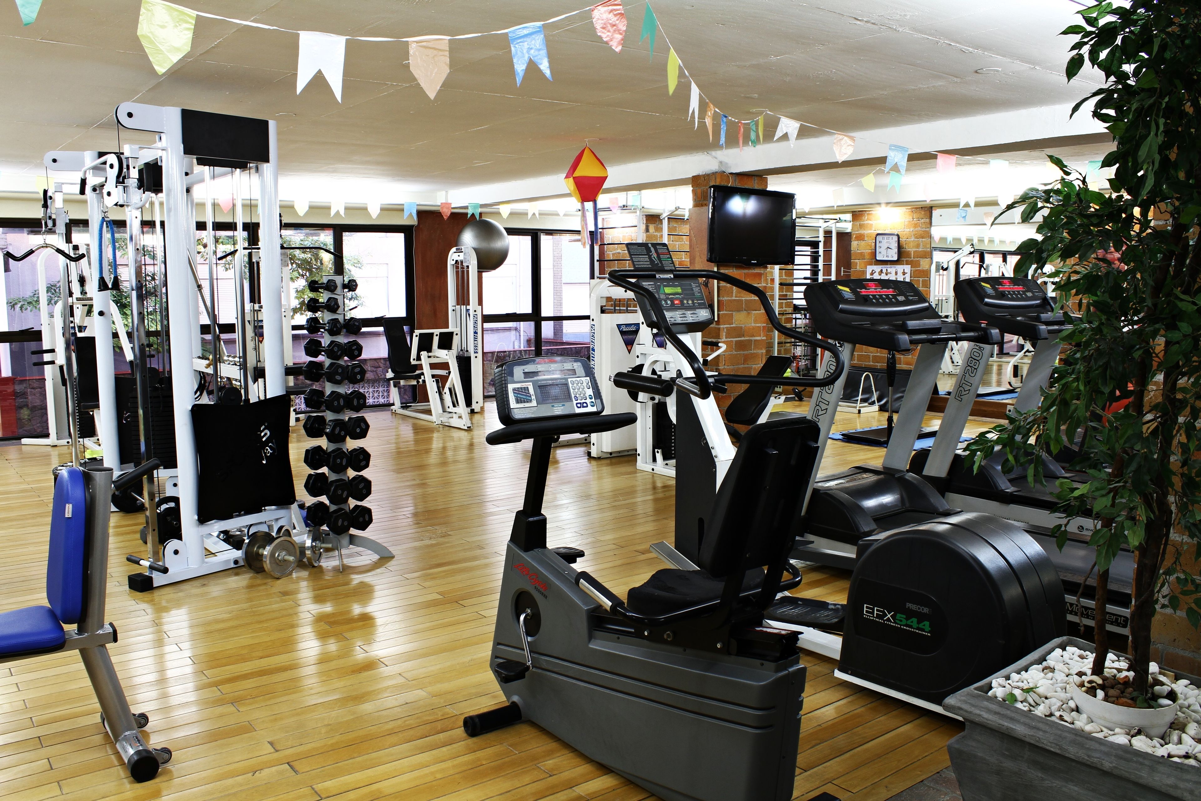 A gym with cardio machines, weightlifting equipment, and a variety of dumbbells.