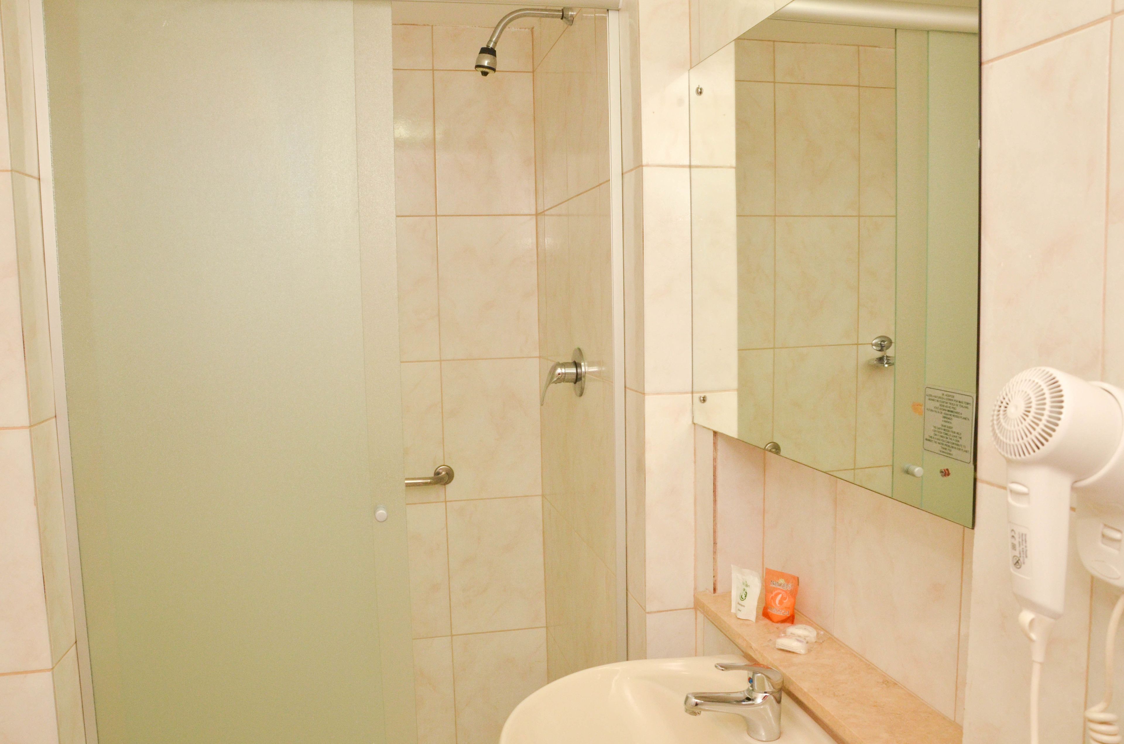 A bathroom with a shower, sink, and a hairdryer on the counter.