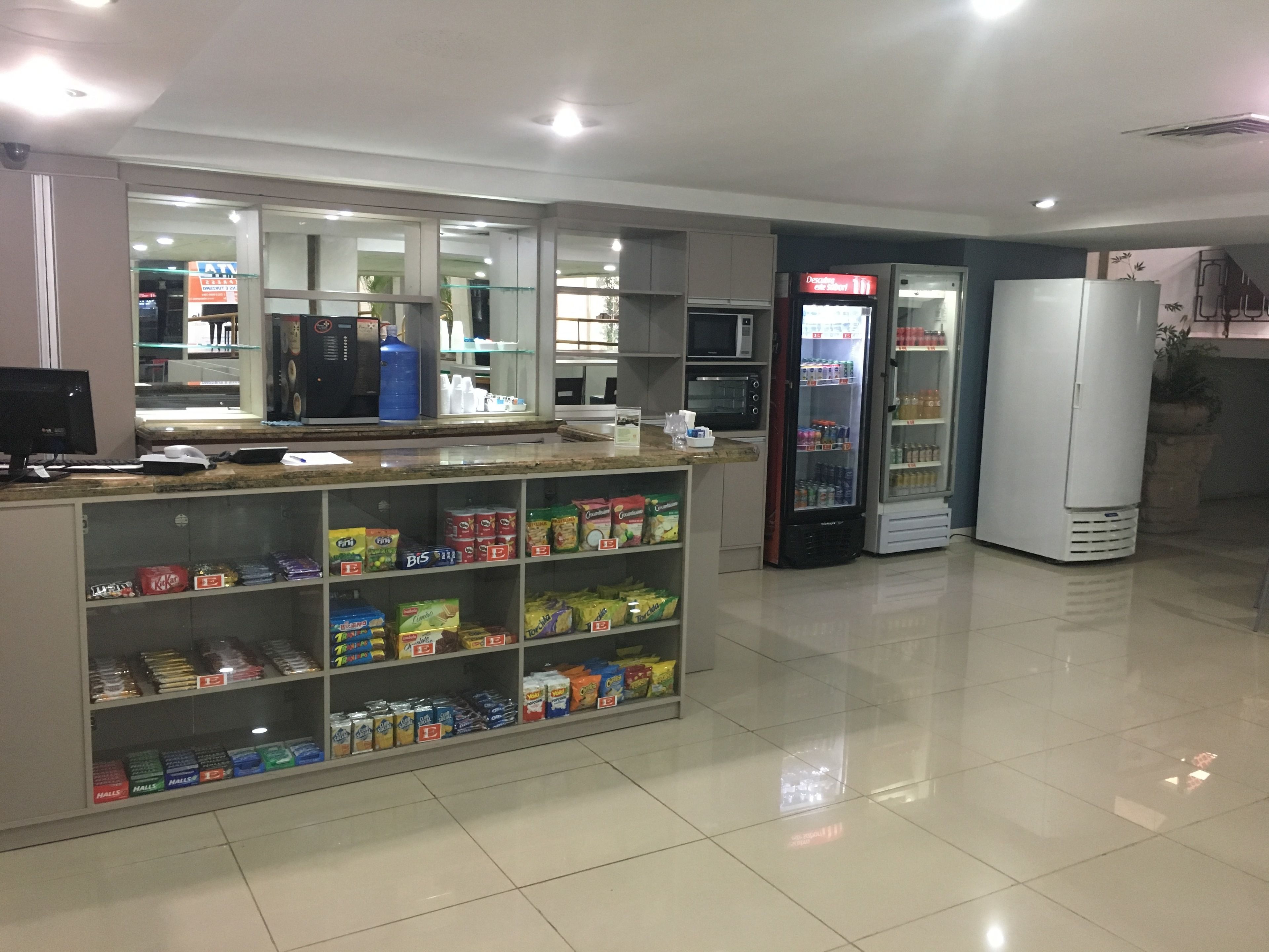 A clean, well-lit convenience store with shelves stocked with snacks and beverages, a microwave, and a refrigerator.