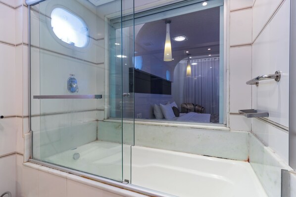 Un baño moderno con cabina de ducha de vidrio, una bañera y vistas al interior a través del cristal.