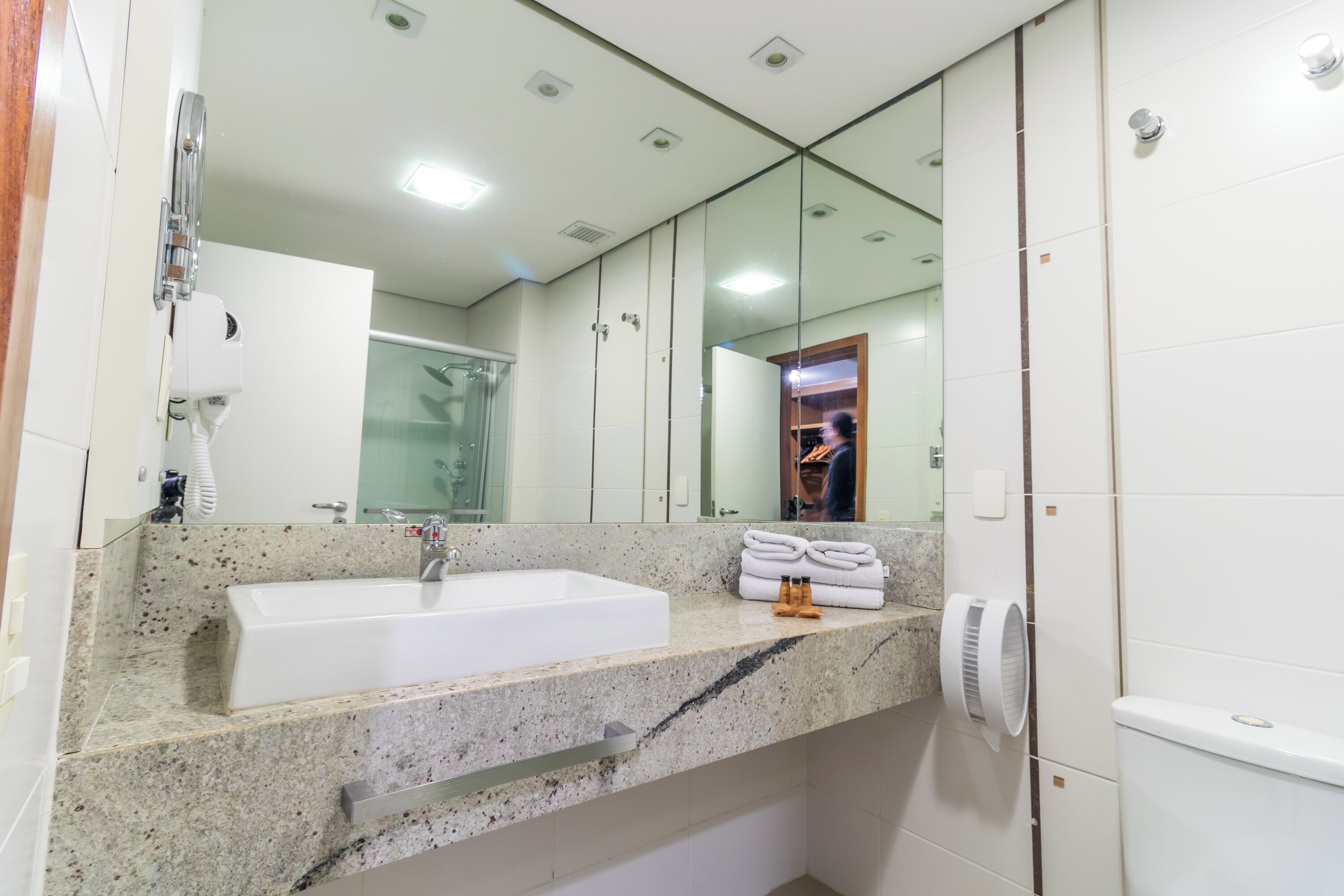 A modern bathroom with a large sink, a mirror, and a towel rack.