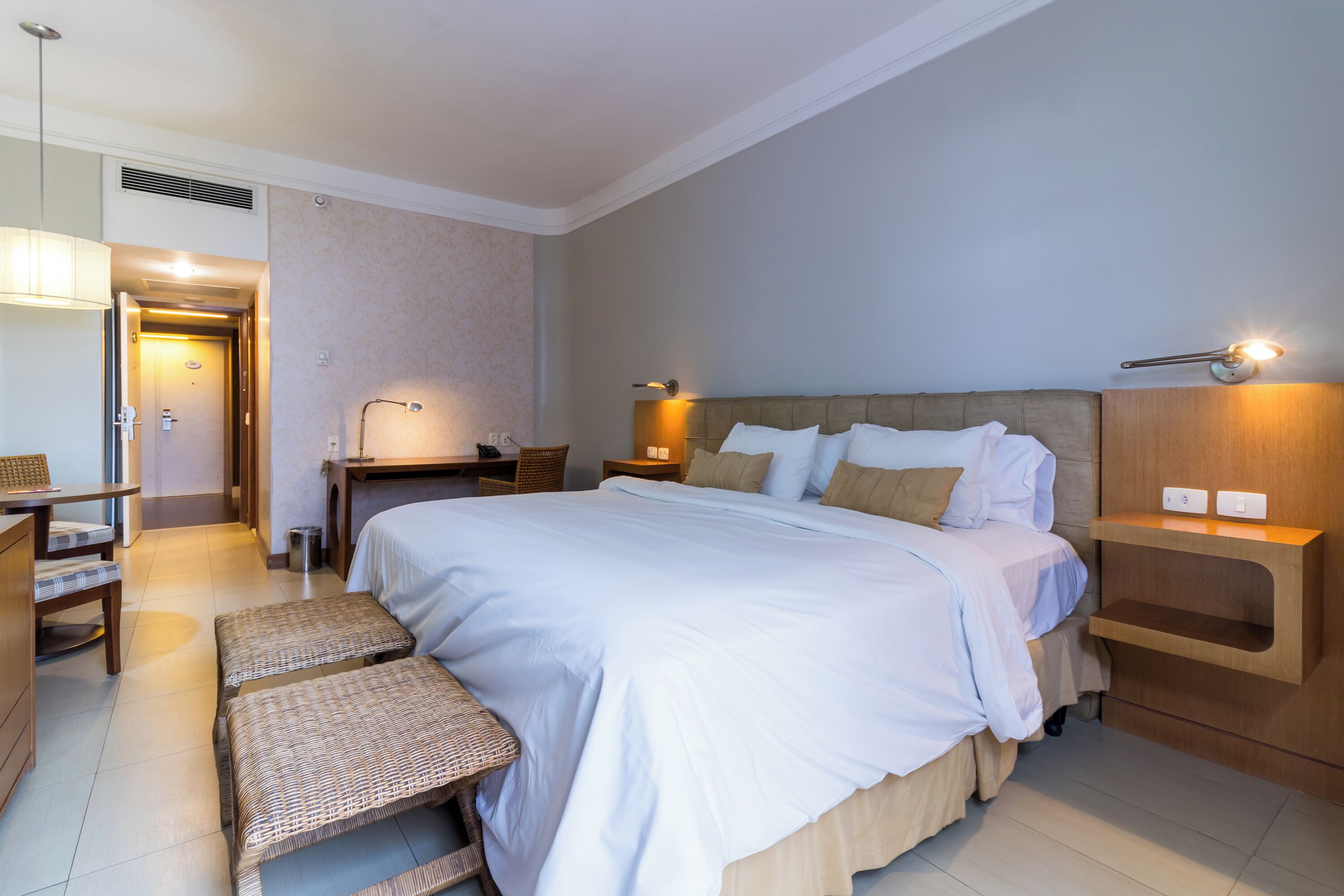 A hotel room with a large bed, bedside tables, a desk, and a chair.