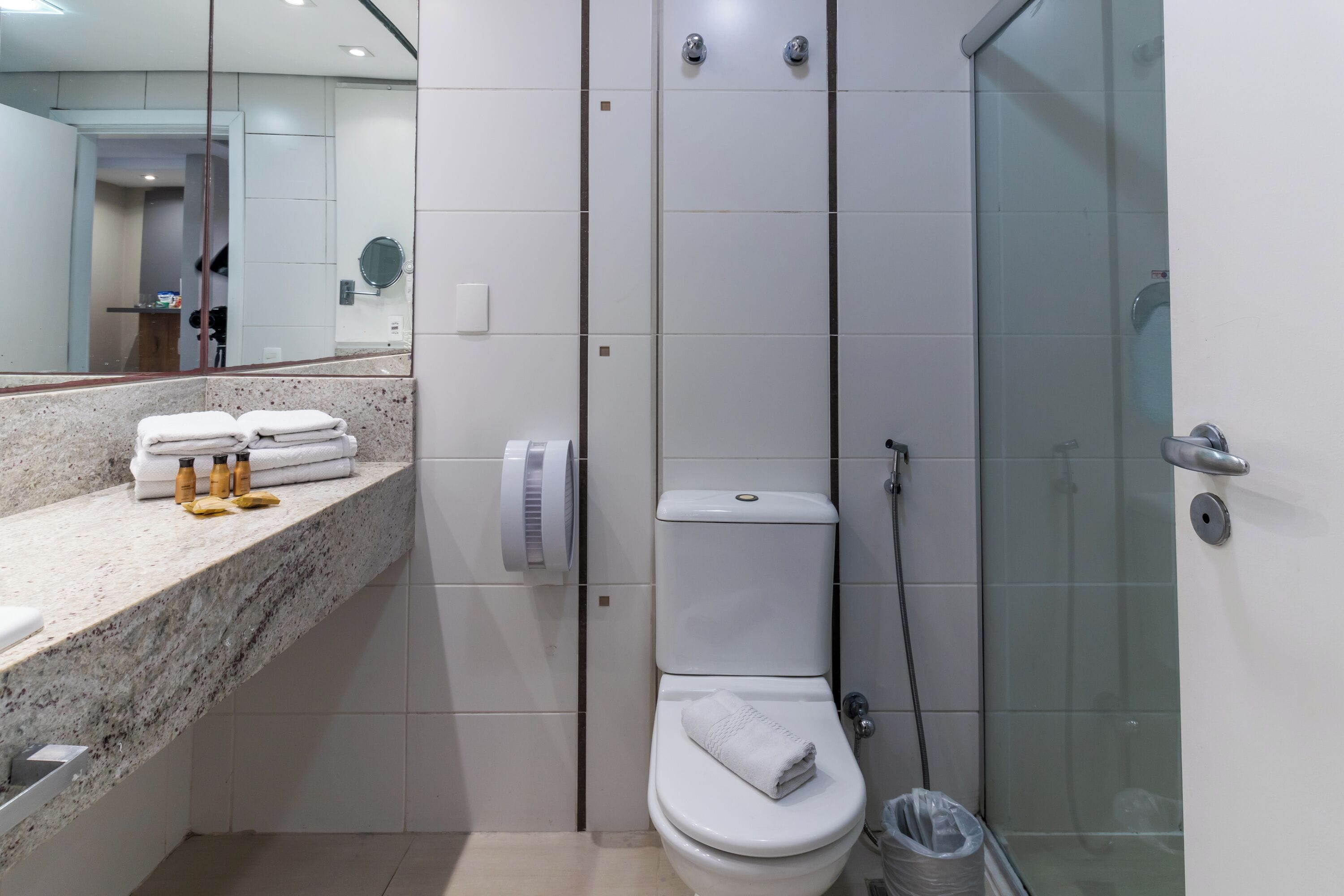 Un baño moderno con encimera de mármol, inodoro, cabina de ducha de vidrio y espejo.
