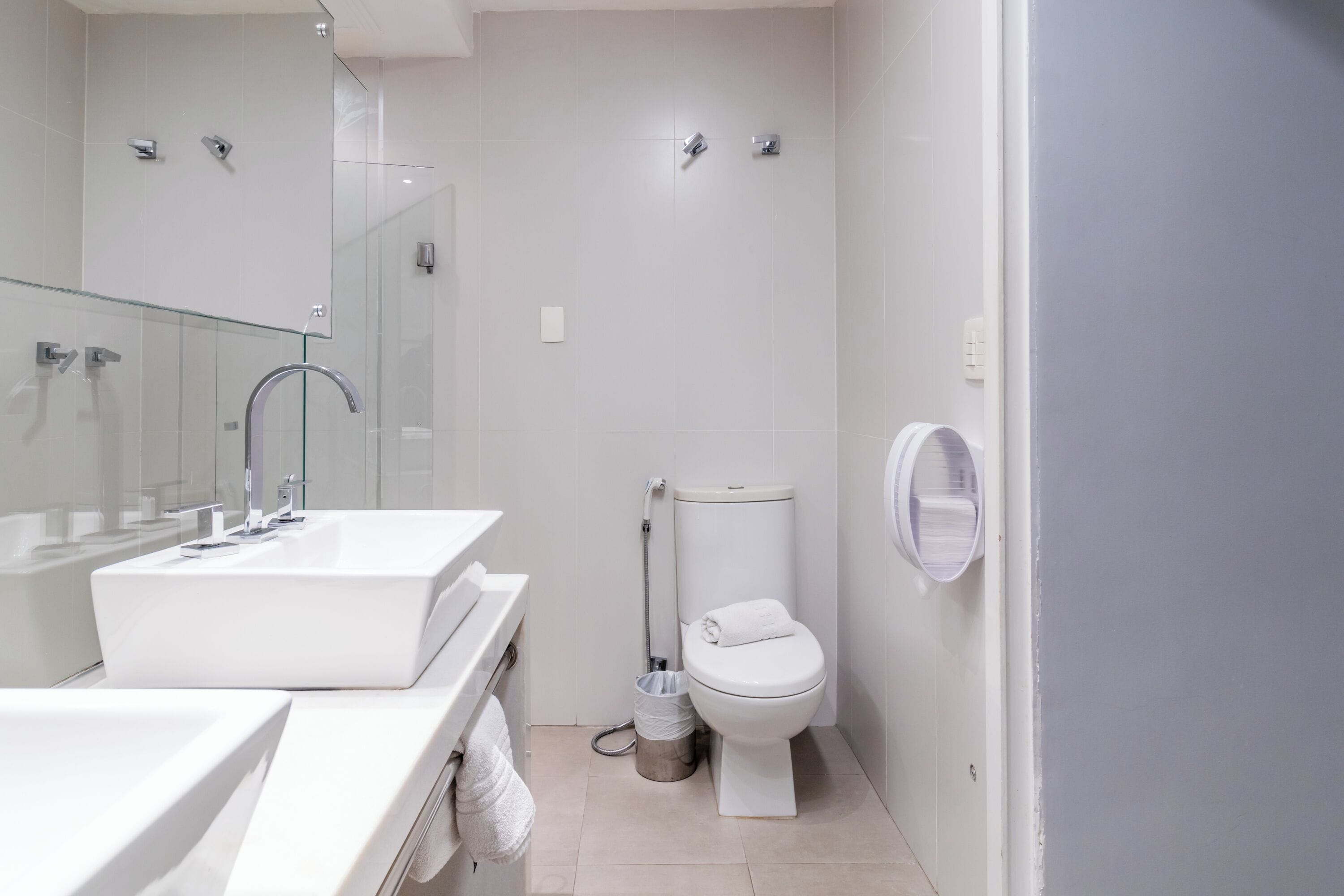 Un baño moderno con un lavamanos grande de color blanco, cabina de ducha con mampara de vidrio y un inodoro.