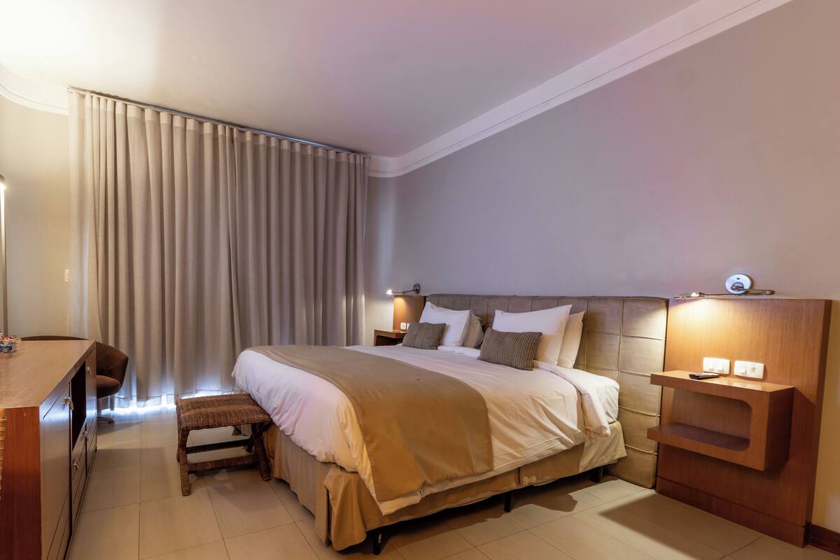 A modern hotel room with a large bed, bedside tables, a desk, and a chair.