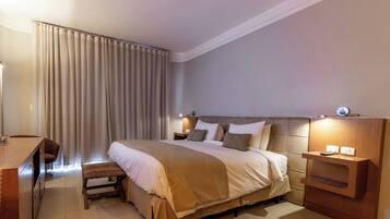 A modern hotel room with a large bed, bedside tables, a desk, and a chair.