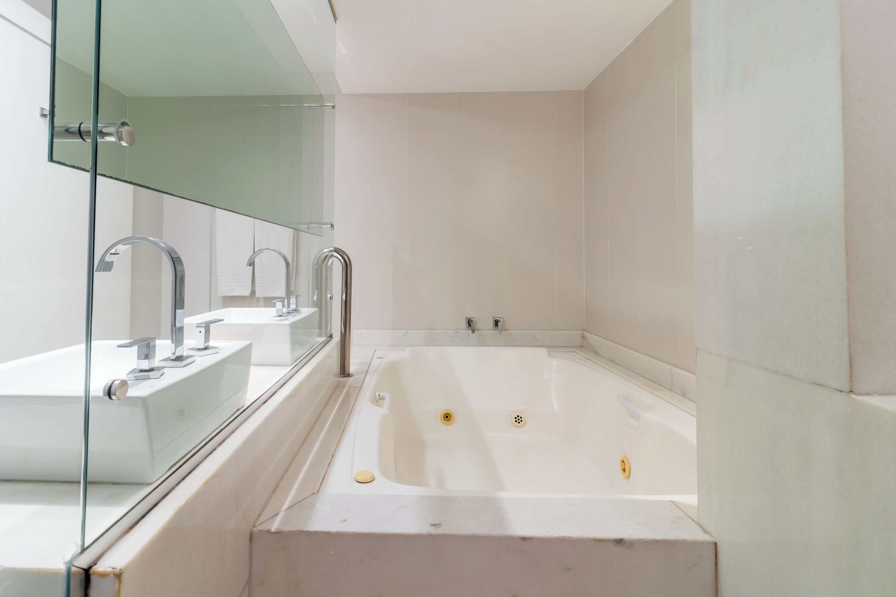 Un baño moderno con una bañera grande, dos lavamanos y una cabina de ducha con mampara de vidrio.