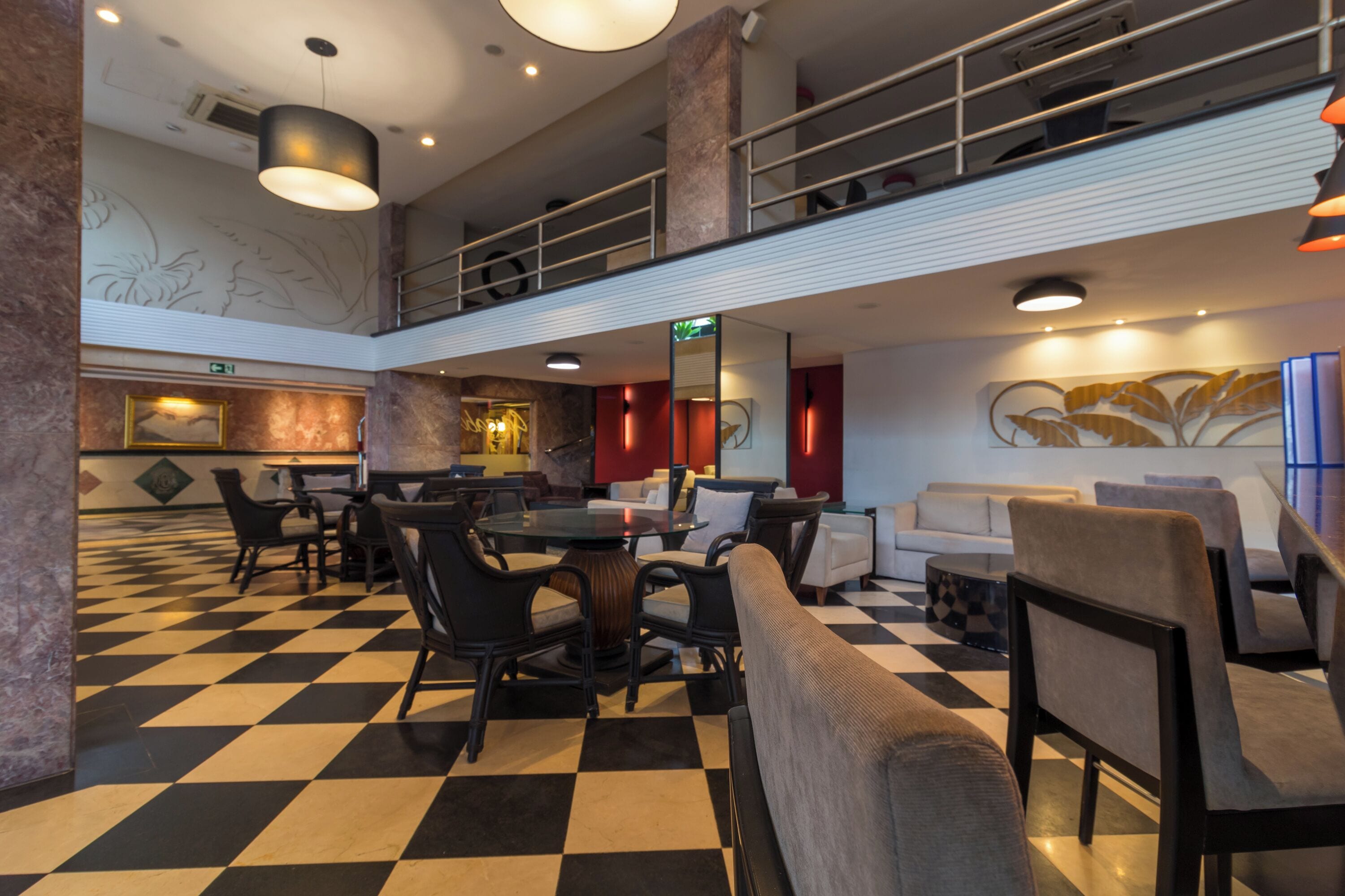 A lobby with a checkered floor, seating areas, a staircase, and a decorative wall.