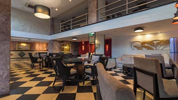 A lobby with a checkered floor, seating areas, a staircase, and a decorative wall.