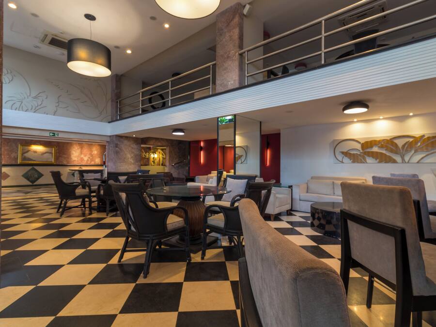 A lobby with a checkered floor, seating areas, a staircase, and a decorative wall.