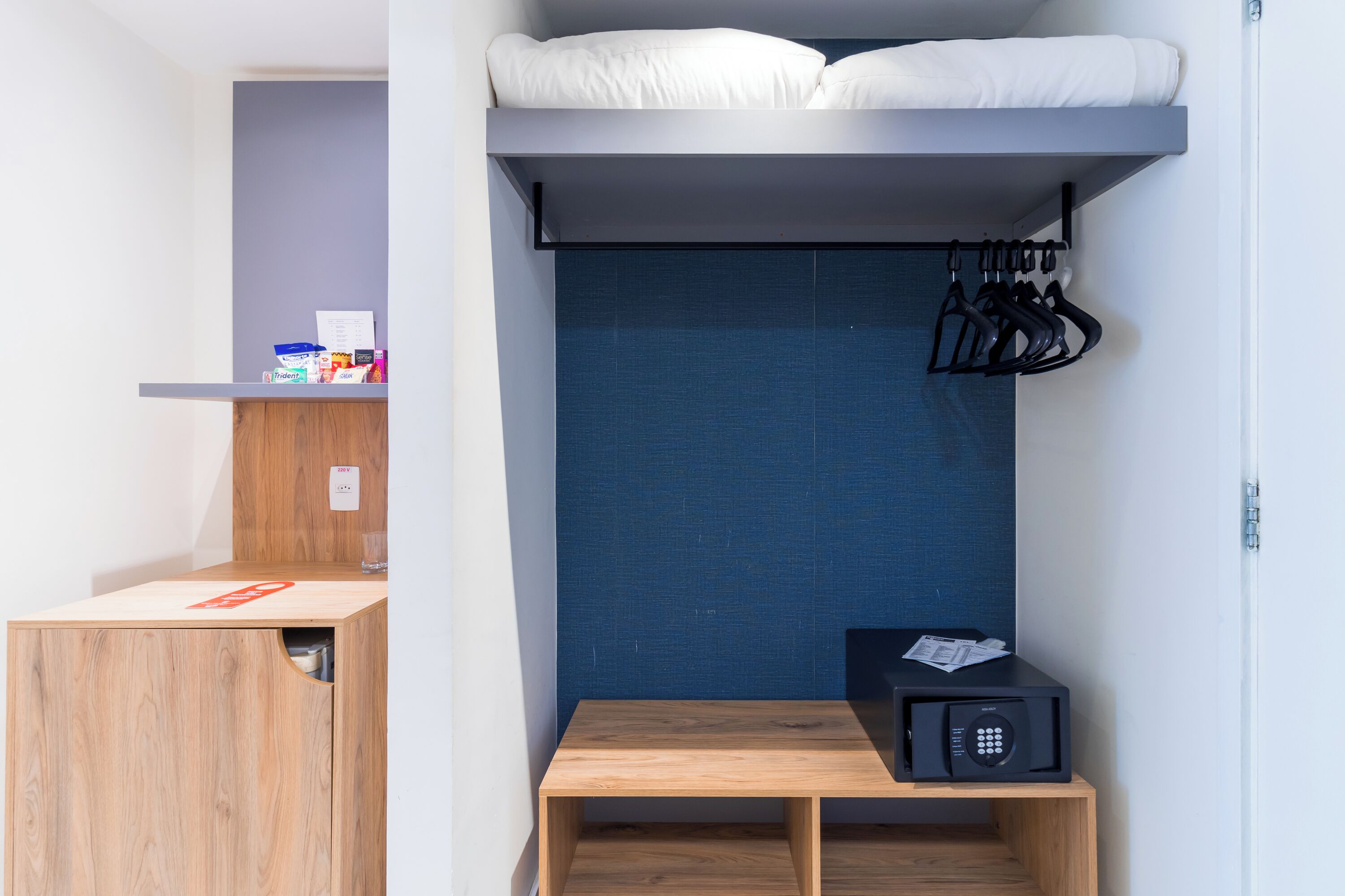 Une petite chambre comprenant un lit superposé, une petite table avec un four à micro-ondes et un porte-chaussures.