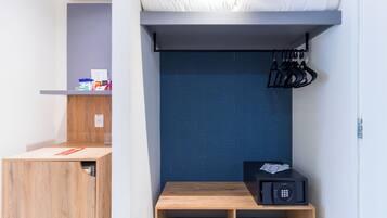 A compact room with a bunk bed, a small table with a microwave, and a shoe rack.