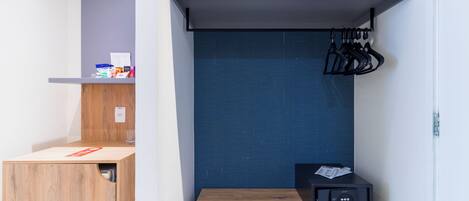 A compact room with a bunk bed, a small table with a microwave, and a shoe rack.
