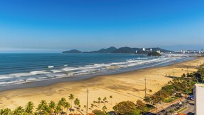 A beach with a clear view of the ocean and distant mountains. - Parque Balneário Hotel Santos by Castelo Itaipava (Santos)