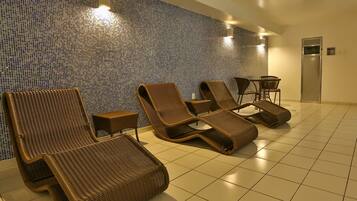 A room with four wicker lounge chairs, a small table, and a wall with a mosaic tile pattern.