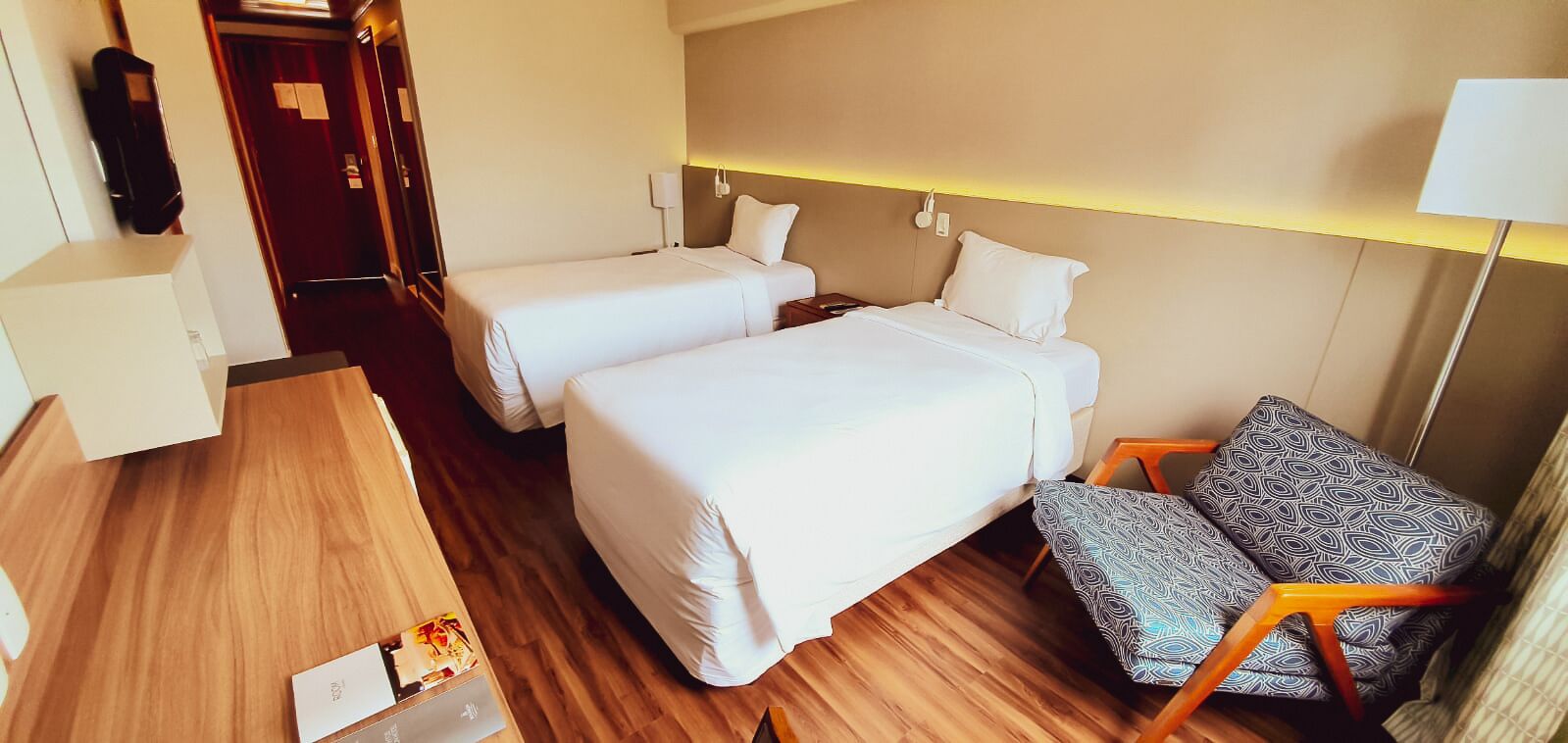 Una habitación de hotel con dos camas, un escritorio, una silla y una mesita de noche.