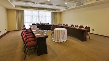 A conference room with a long table, red chairs, and a white tablecloth.