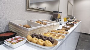 A buffet with various food items including pastries, donuts, and a bowl of soup.