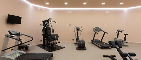Un gimnasio con cintas de correr, elípticas y equipo de pesas.