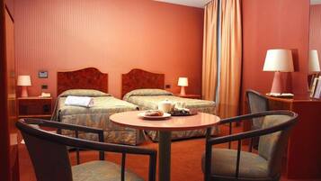 Habitación de hotel con dos camas, una mesa redonda y dos sillas.