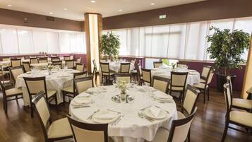 Comedor con mesas redondas dispuestas para varios comensales, con manteles blancos y sillas.