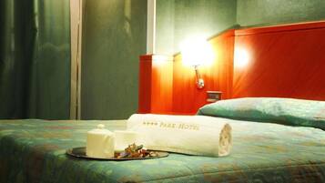 Habitación de hotel con una cama bien hecha, una lámpara de noche y una bandeja con una taza y un recipiente pequeño.