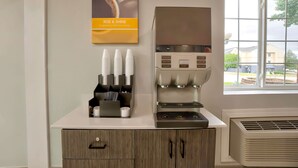 Une machine à café dotée d’un porte-tasse et une fenêtre donnant sur des immeubles.