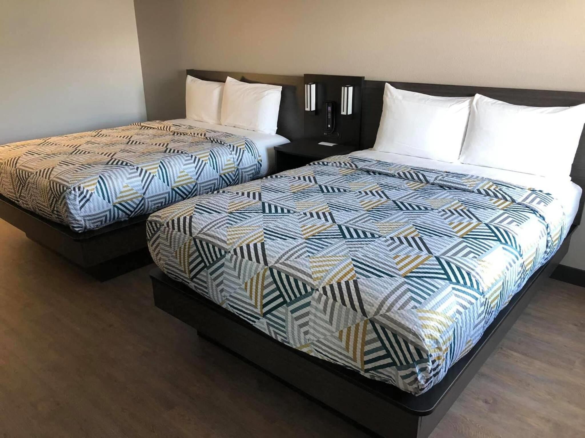 Un lit double avec une couvre-lit à motifs géométriques et deux oreillers.