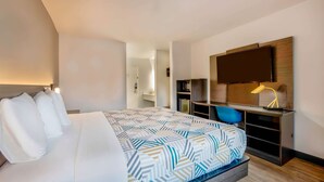 Une chambre d’hôtel moderne dotée d’un grand lit, d’un bureau avec une chaise, d’un téléviseur à écran plat et d’une lampe de bureau.