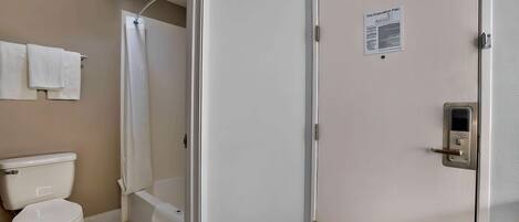 Ein Badezimmer mit Toilette, Dusche und Badewanne. Eine Tür mit einem Brandschutzplan.