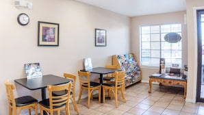Um quarto com uma mesa, cadeiras, um relógio e quadros na parede.