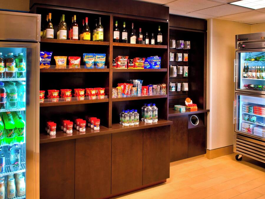 A well-stocked beverage refrigerator and pantry area with various drinks, snacks, and condiments.