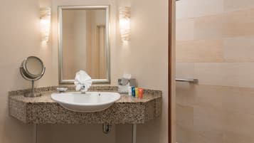A bathroom with a granite countertop, a white sink, a mirror, and a towel hanging on the wall.