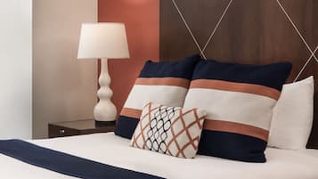 A neatly made bed with a patterned pillow, a bedside table with a lamp, and a wooden headboard.