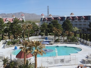 Relax by the pool surrounded by lush greenery and palm trees, with lounge chairs and umbrellas at your disposal.