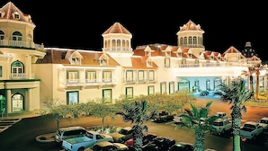 A hotel with multiple stories, a central courtyard, and a parking area with several cars.