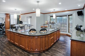 A large kitchen island with a wood finish, equipped with a sink and various food items. - Staybridge Suites Round Rock by IHG (Round Rock)