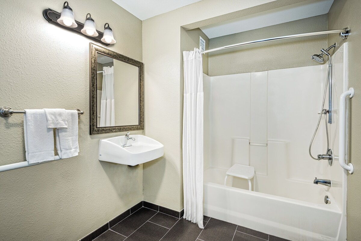 A bathroom with a white sink, mirror, and shower.
