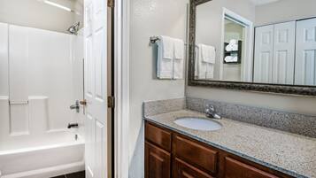 A bathroom with a bathtub, a sink, and a mirror.
