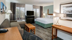 A hotel room with a sofa, a bed, a desk, a television, and a window with curtains. - Staybridge Suites Round Rock by IHG (Round Rock)