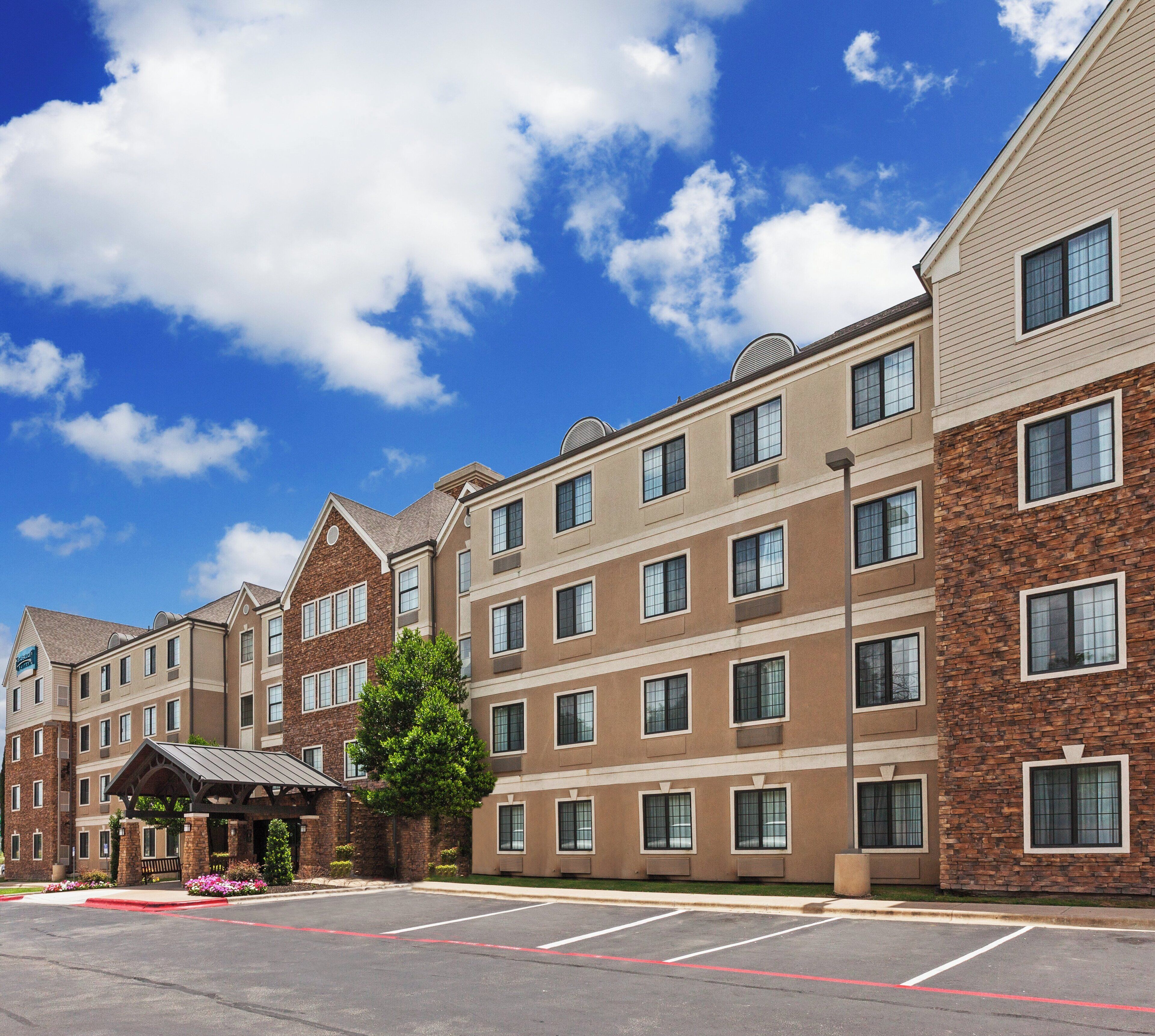 A multi-story hotel with a brick facade, a covered entrance, and a parking lot.