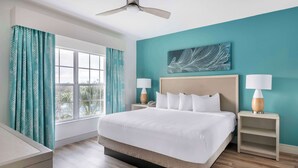 Habitación de hotel con una cama grande, dos mesitas de noche con lámparas, un ventilador de techo y una ventana con cortinas.