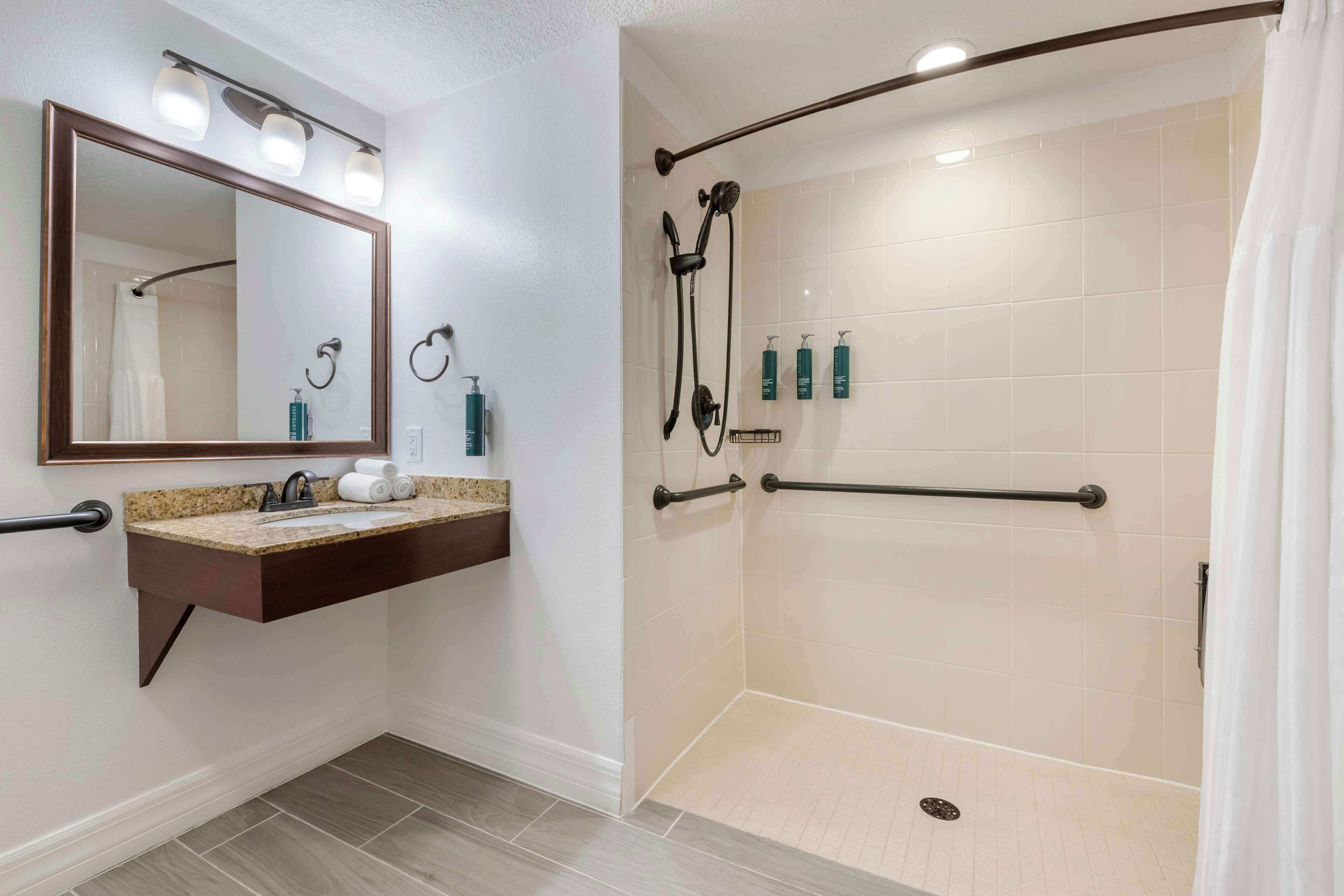 A bathroom with a sink, mirror, and shower.