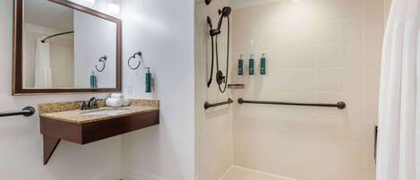 A bathroom with a sink, mirror, and shower.