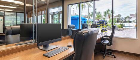 A modern office with a large window, a desk with a computer, and a chair.