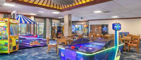 A room with pool tables, arcade games, and wooden furniture.