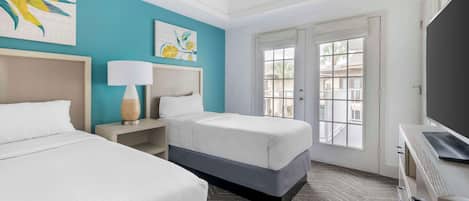 Une chambre d’hôtel avec deux lits, un ventilateur de plafond, une grande fenêtre et un téléviseur.
