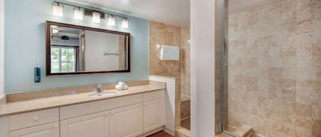 Un baño con un espejo grande, un lavamanos y una ducha.