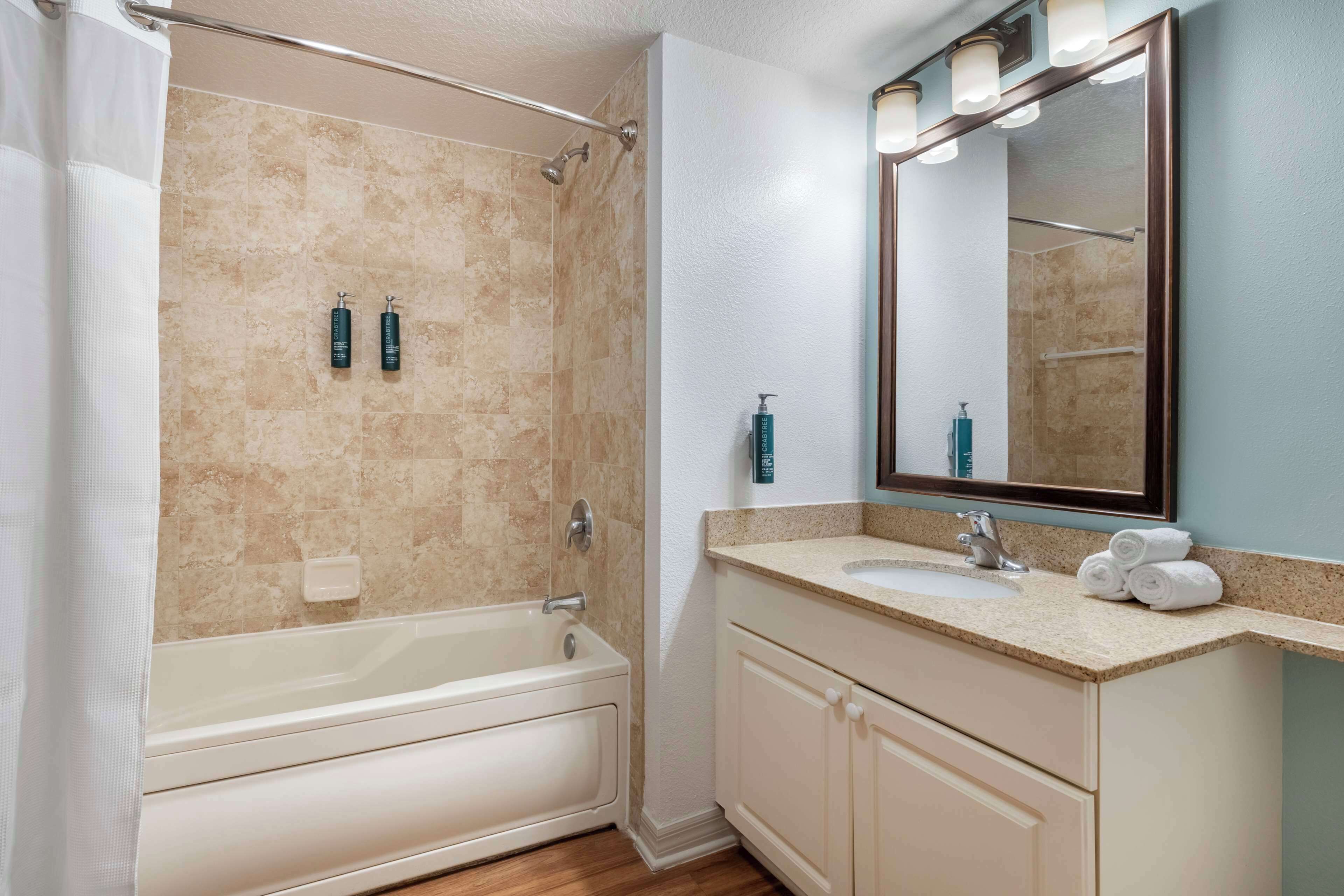 A bathroom with a bathtub, a sink, and a mirror.