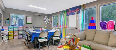 A classroom with tables, chairs, and educational materials.
